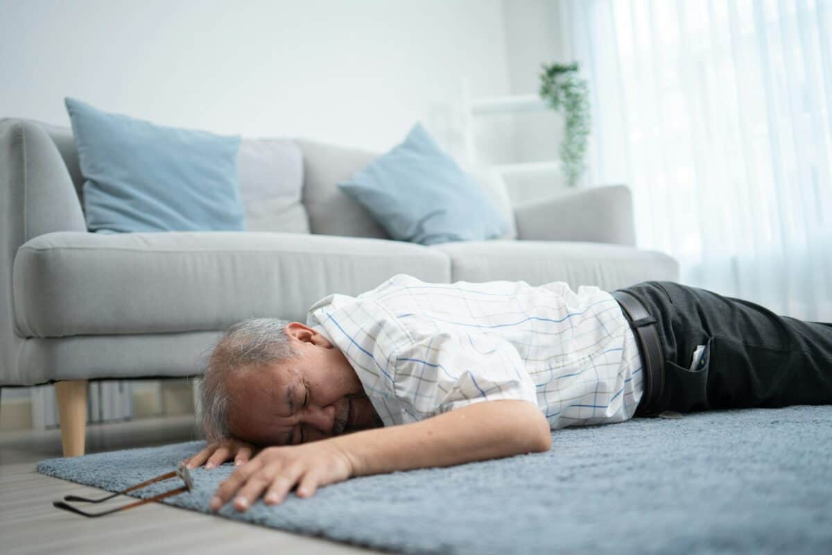 Asian senior grandfather fainting and falling on the ground in the living room