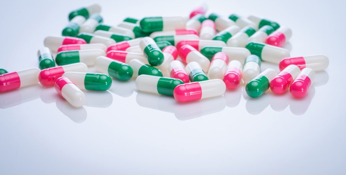 Capsules pill spread on white background. Prescription drugs. Capsule pill production. Green, pink,