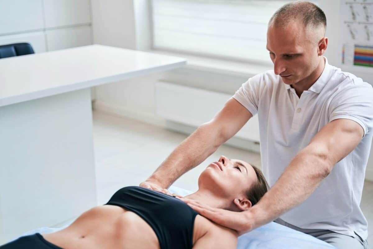 Charmante femme allongée sur un divan médical lors d'une thérapie manuelle professionnelle dans un centre de bien-être.