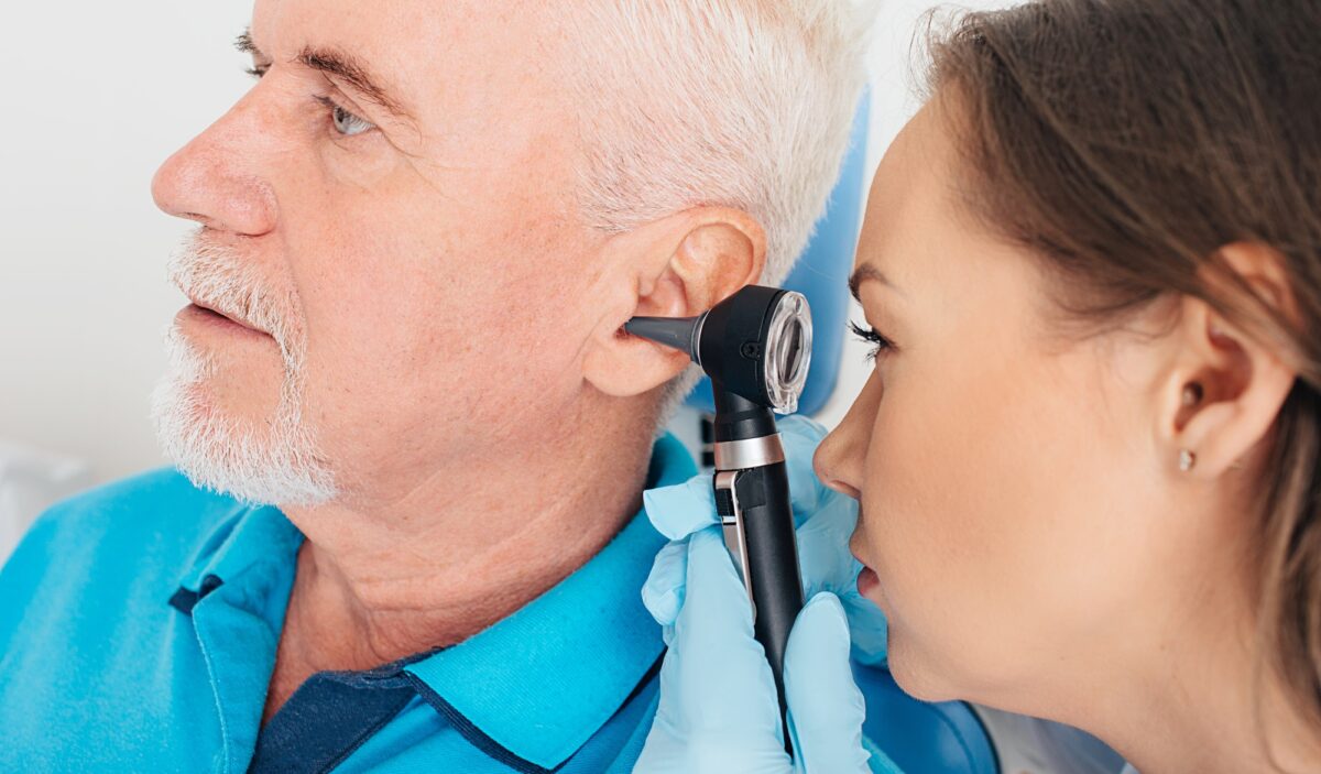 Examen de l'audition. Patient âgé lors d'un test auditif, un médecin avec un otoscope vérifiant l'audition.