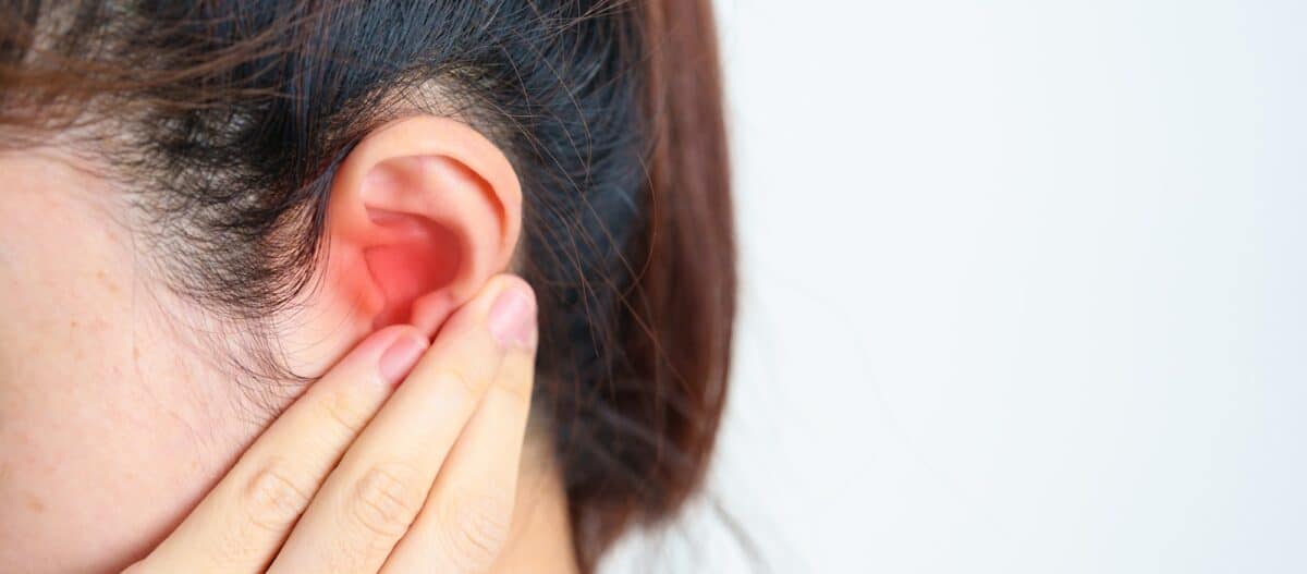 Femme tenant son oreille douloureuse. Maladie de l'oreille, Atrésie