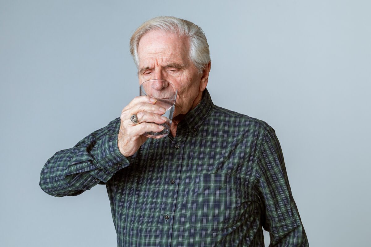 Homme âgé buvant un verre d'eau
