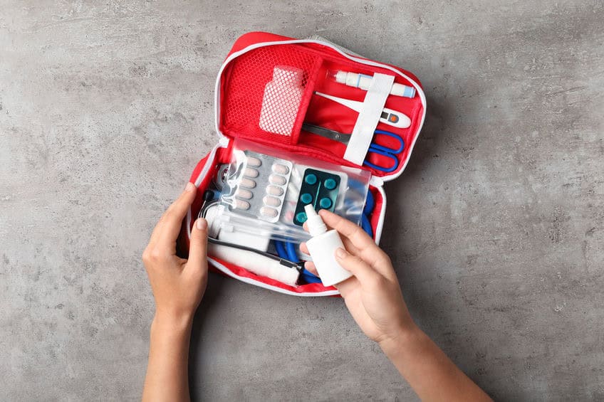 Femme avec trousse de premiers secours sur fond gris, vue de dessus