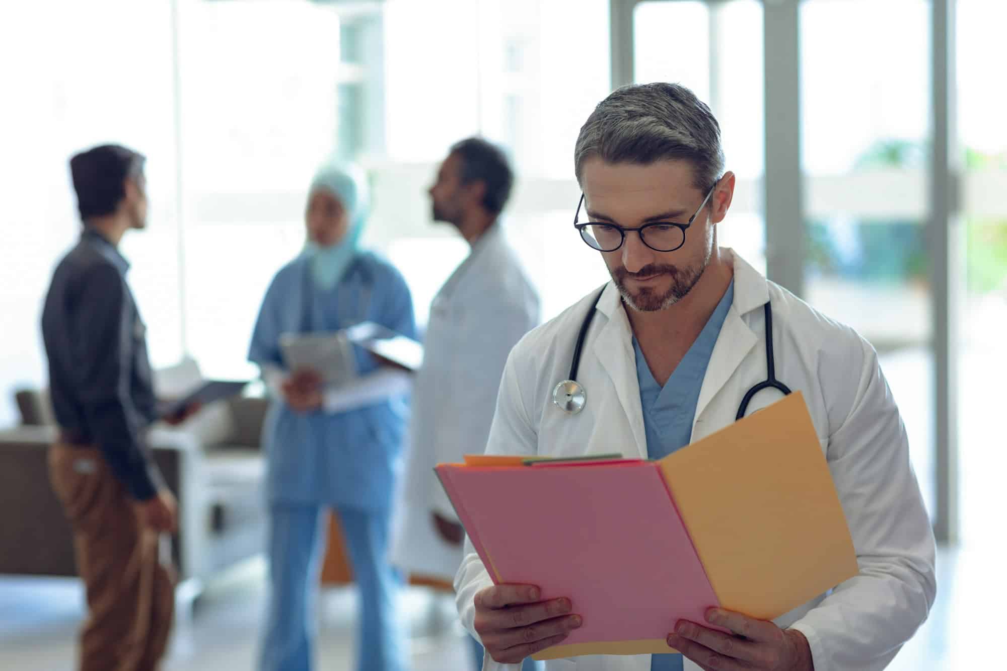 Médecin caucasien consultant un dossier médical dans un hôpital.