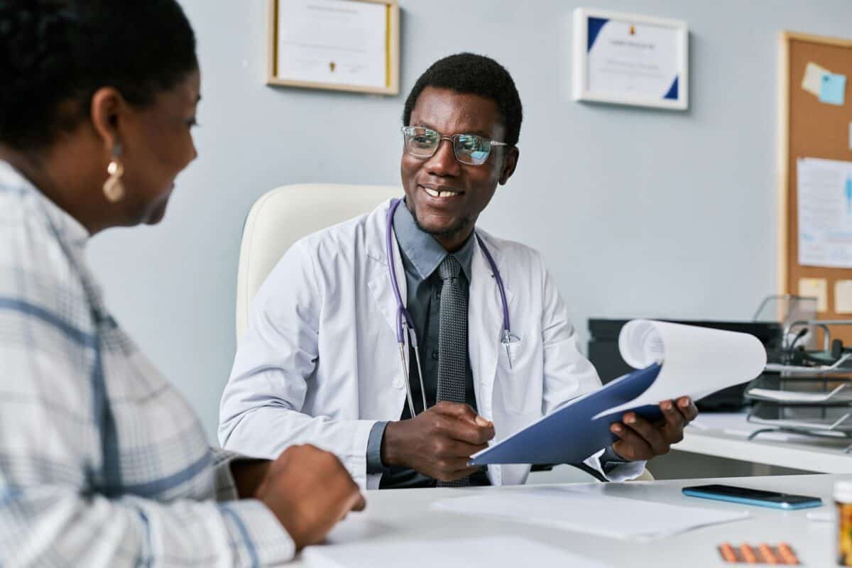 Médecin noir souriant consultant une femme médecin dans une clinique