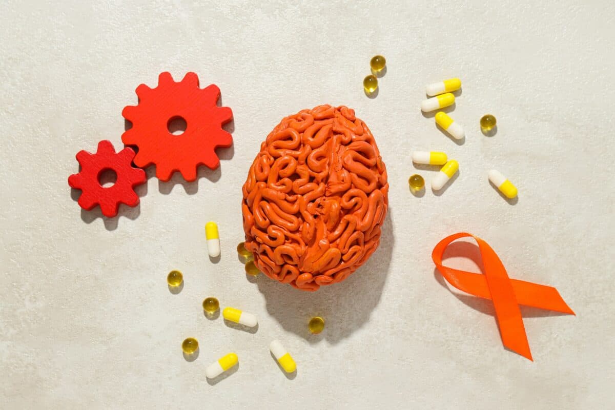 Modèle de cerveau humain orange avec pilules et engrenages