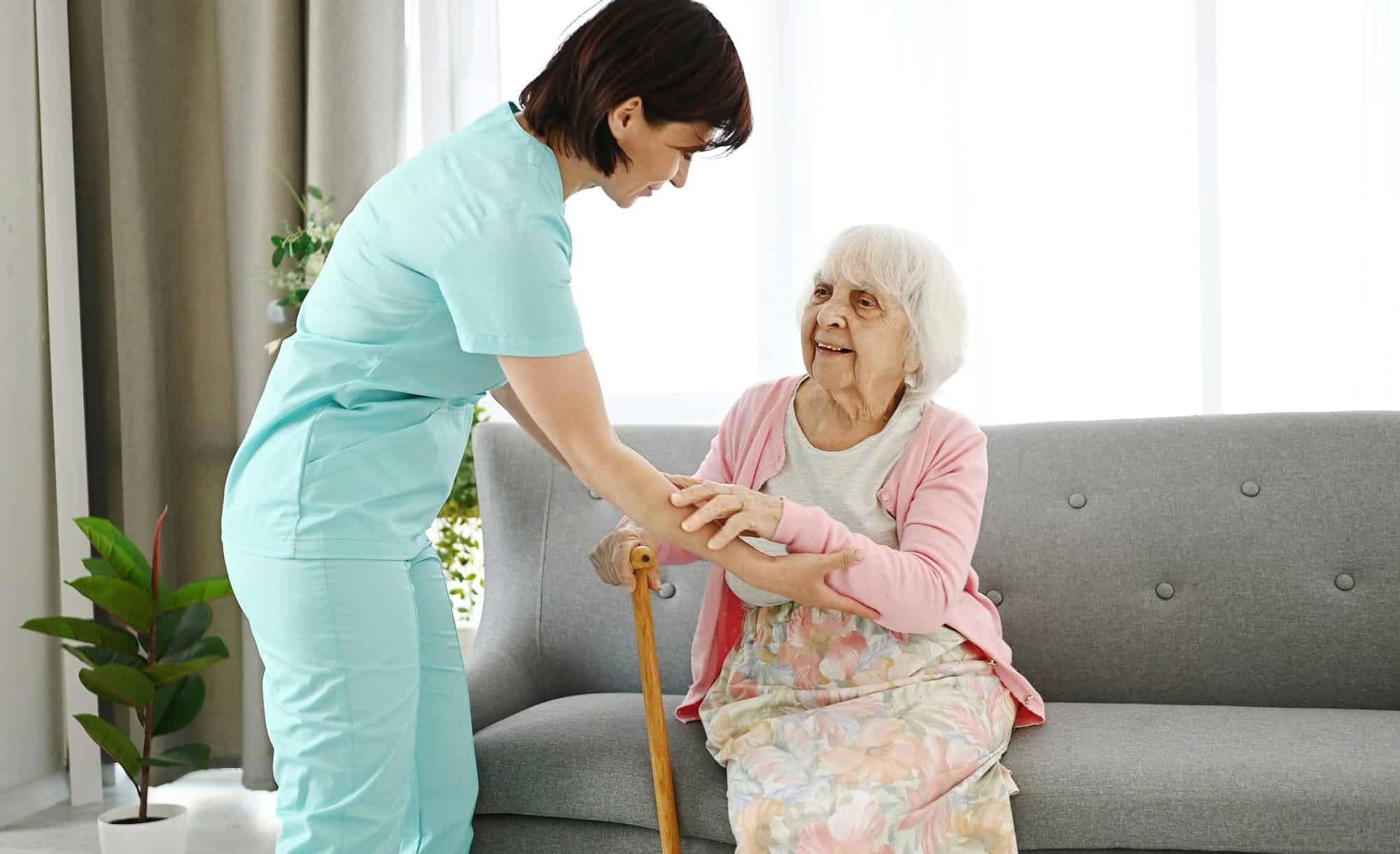 Nurse Hands Cane To Elderly Woman, Helping Her Move Around Room