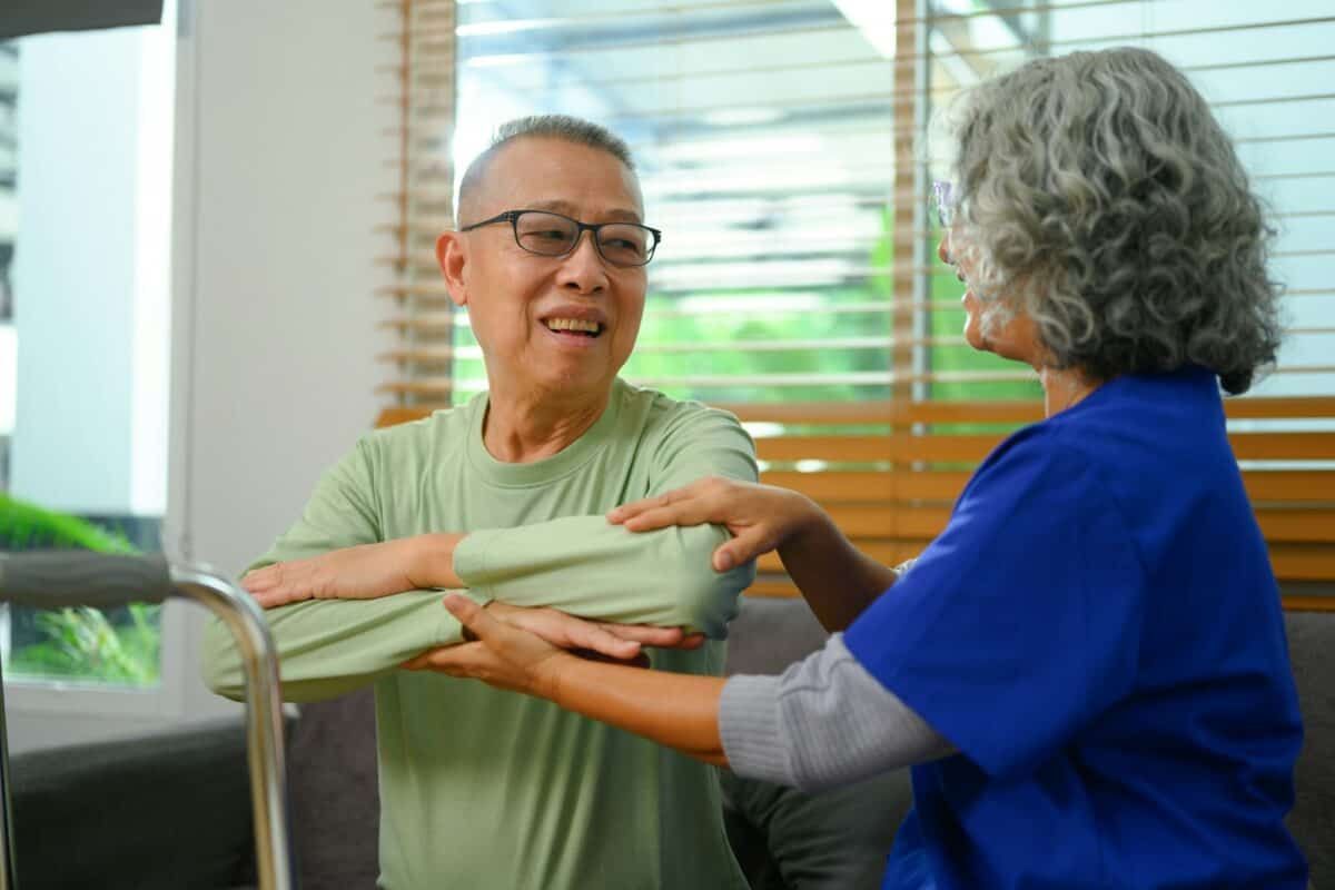 Patient âgé faisant des exercices physiques avec son physiothérapeute à domicile.