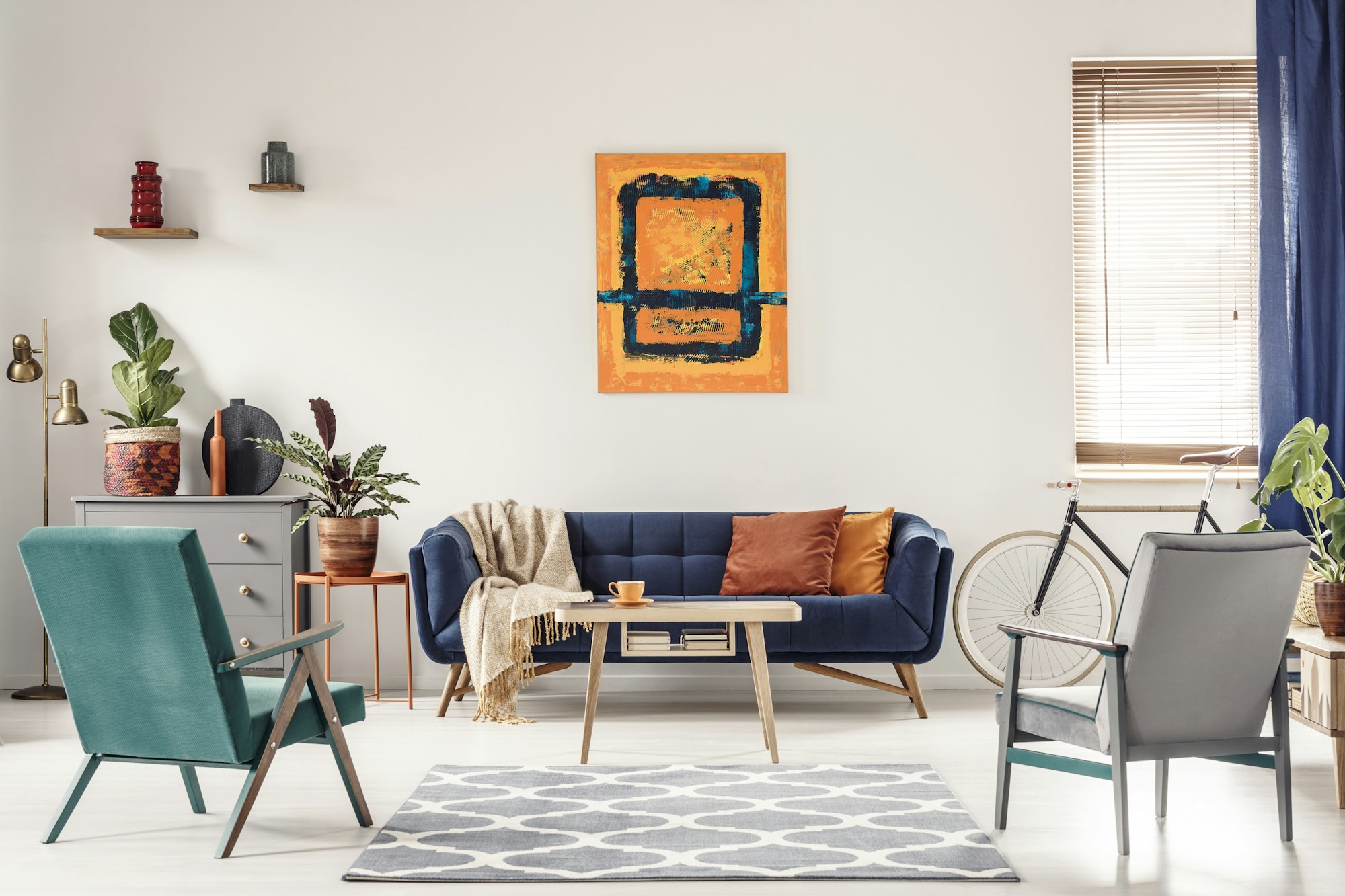 Photo réelle d'un canapé bleu marine avec des coussins oranges et un tableau d'art.