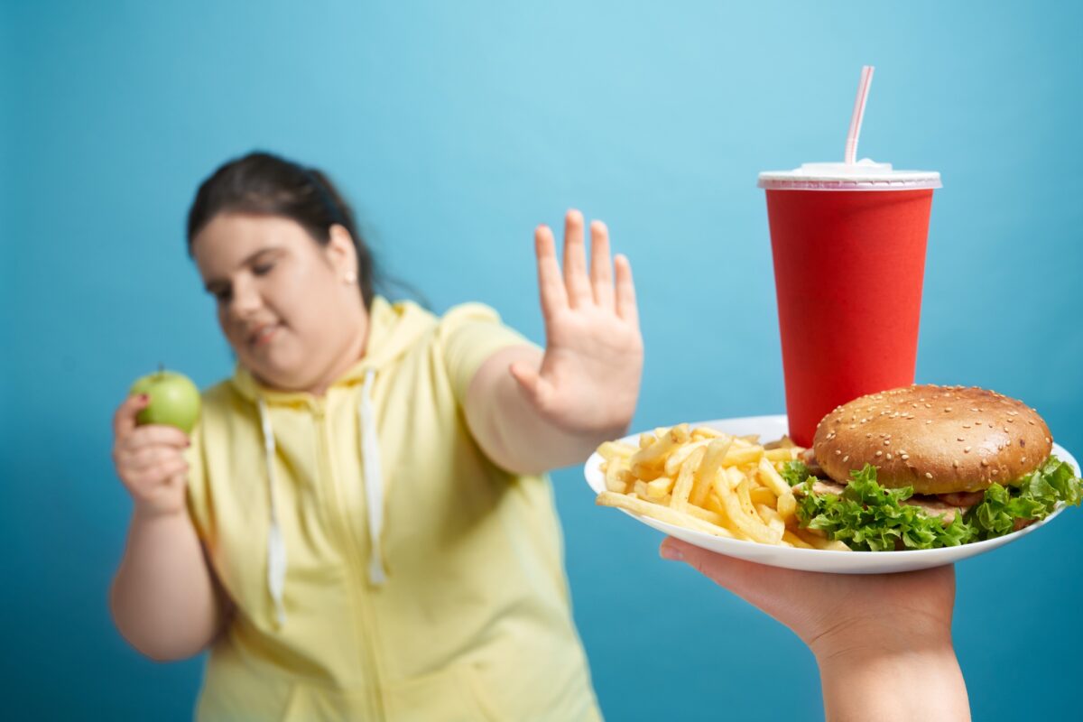 Portrait d'une grosse dame poussant une assiette de fastfood