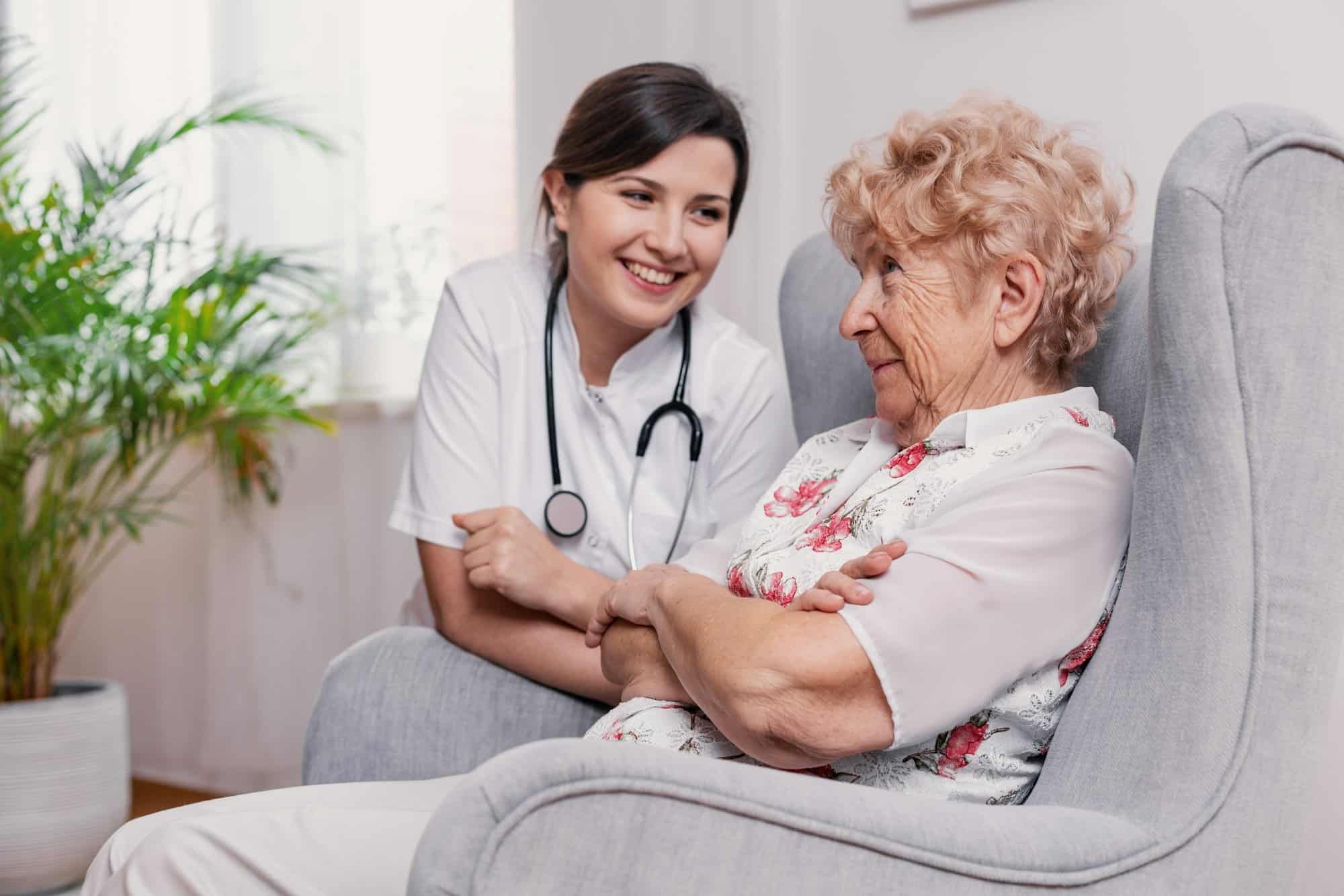 Senior seating on armchair in nursing home and talking to doctor