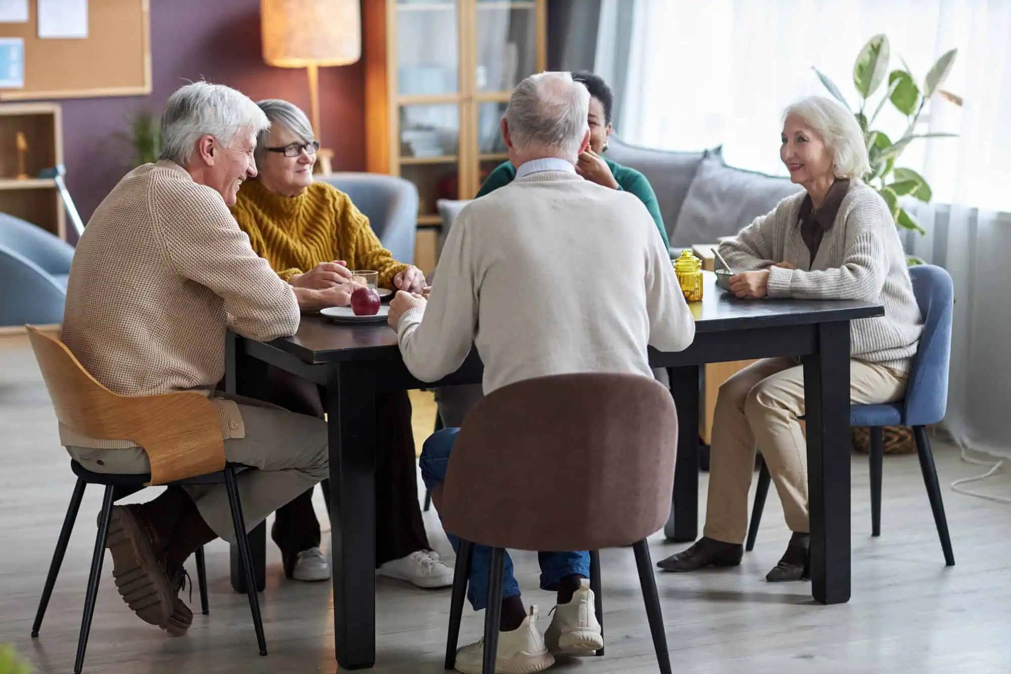 Seniors sitting at table together and smiling happily in retirement home