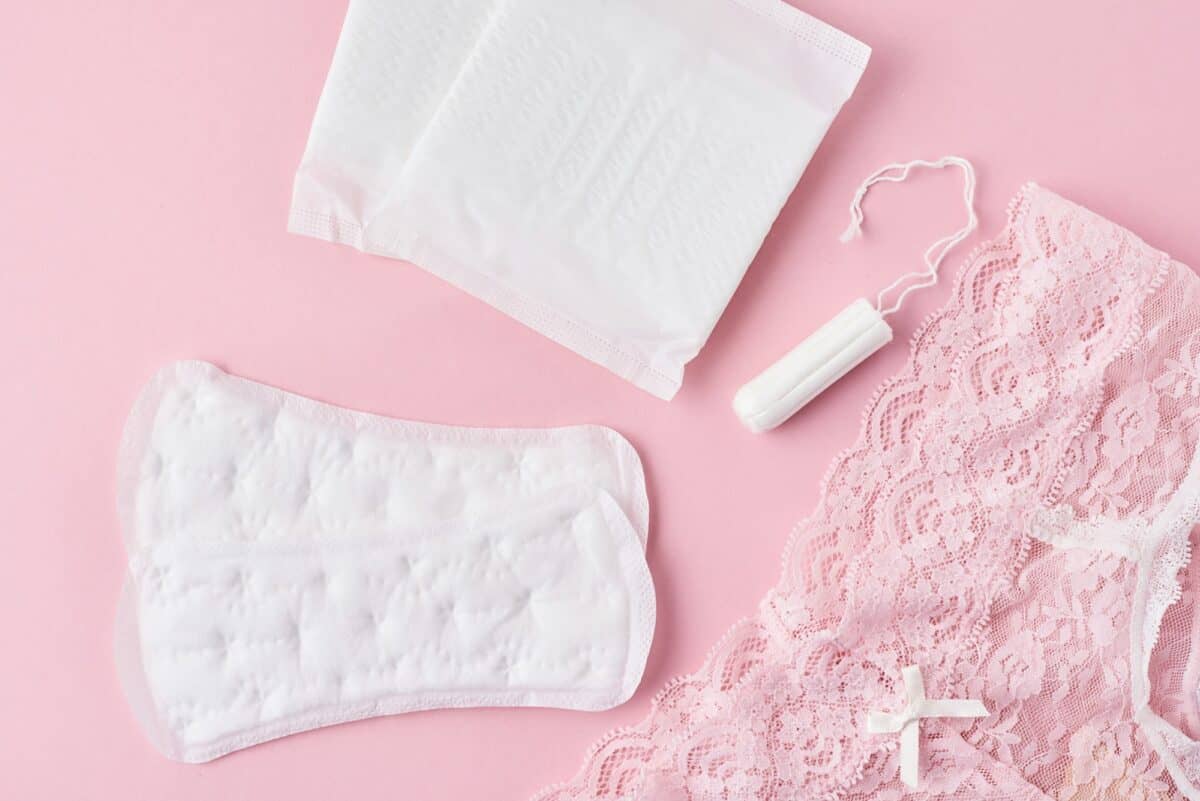 Serviette hygiénique, coupe menstruelle, tampon et culotte sur fond rose