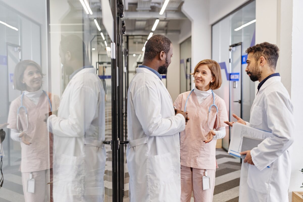 Trois professionnels de la santé contemporains en blouse de laboratoire en train de discuter