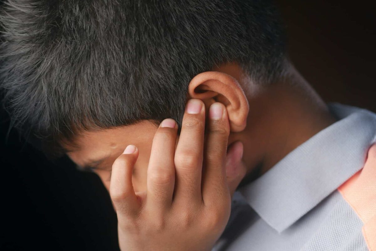 Un adolescent souffrant de douleurs à l'oreille touche son oreille douloureuse,