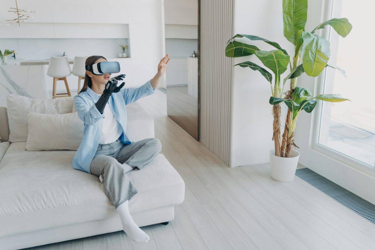 Une fille handicapée avec un bras cybernétique dans des lunettes vr à la maison. Technologie pour le rétablissement et la réadaptation.