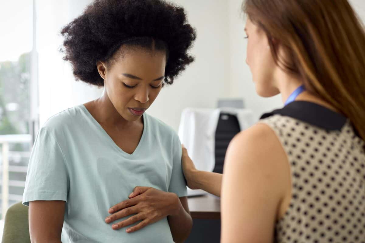 Unhappy Pregnant Woman With Depression At Appointment With Female Doctor Or GP In Office